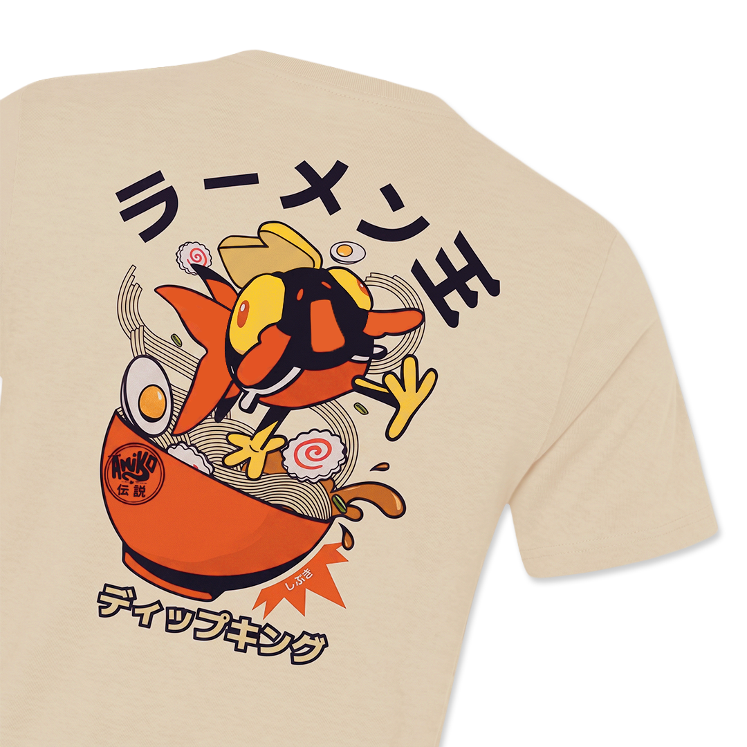 A close-up of a beige t-shirt showing a large graphic print on the back. The graphic features a Amiko Lgends character resembling a ramen noodle in an orange bowl with Japanese text.
