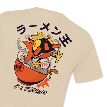 A close-up of a beige t-shirt showing a large graphic print on the back. The graphic features a Amiko Lgends character resembling a ramen noodle in an orange bowl with Japanese text.
