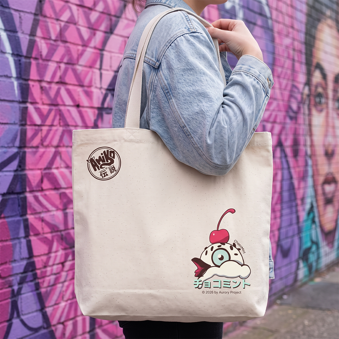A person carries a cream canvas tote bag with a Amiko Legends character graphic and a circular logo patch. The background is a colorful graffiti brick wall.