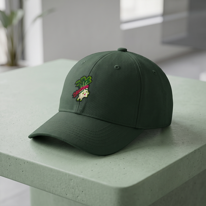 A dark green baseball cap with a pixel-art Amiko Legends character on the front, resting on a light sage green table